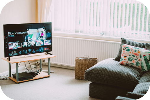 Un salon avec un canapé et une télé ouverte sur netflix pour voir le catalogue des films disponibles